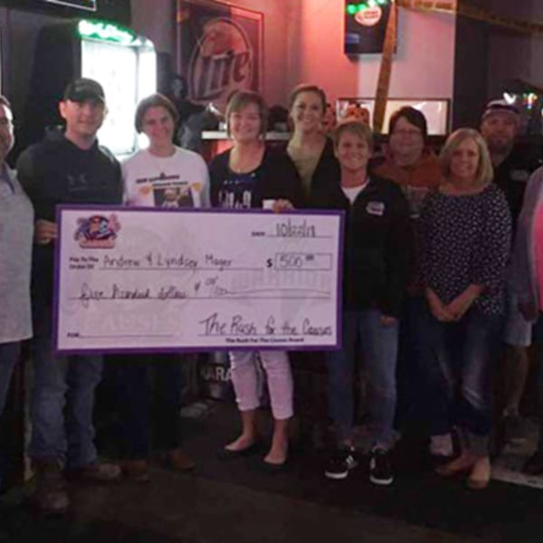 A group of people from The Rush Bar & Grill holding a large check for $500.