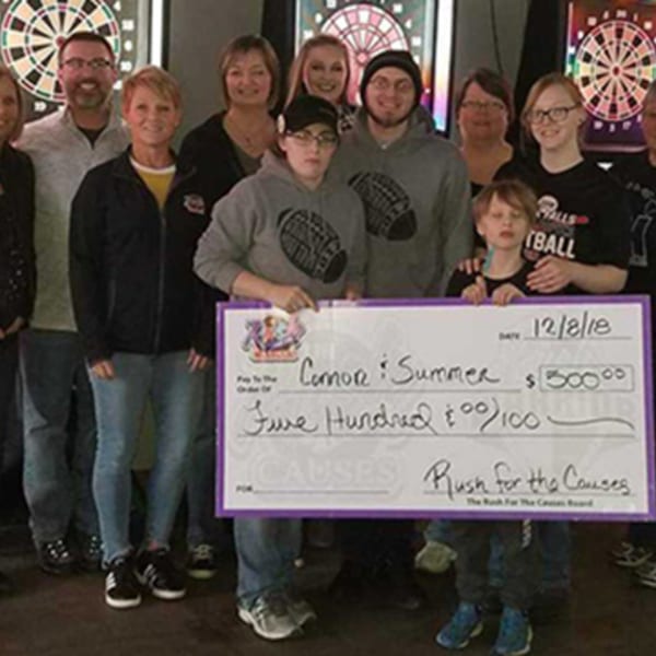 A group of people, including children, holding a large check for $500 from Rush for the Causes.