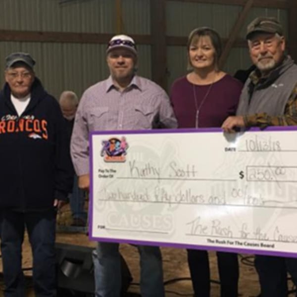 Four people holding a large check for $250.00 made out to Kathy Scott from The Rush for the Causes.
