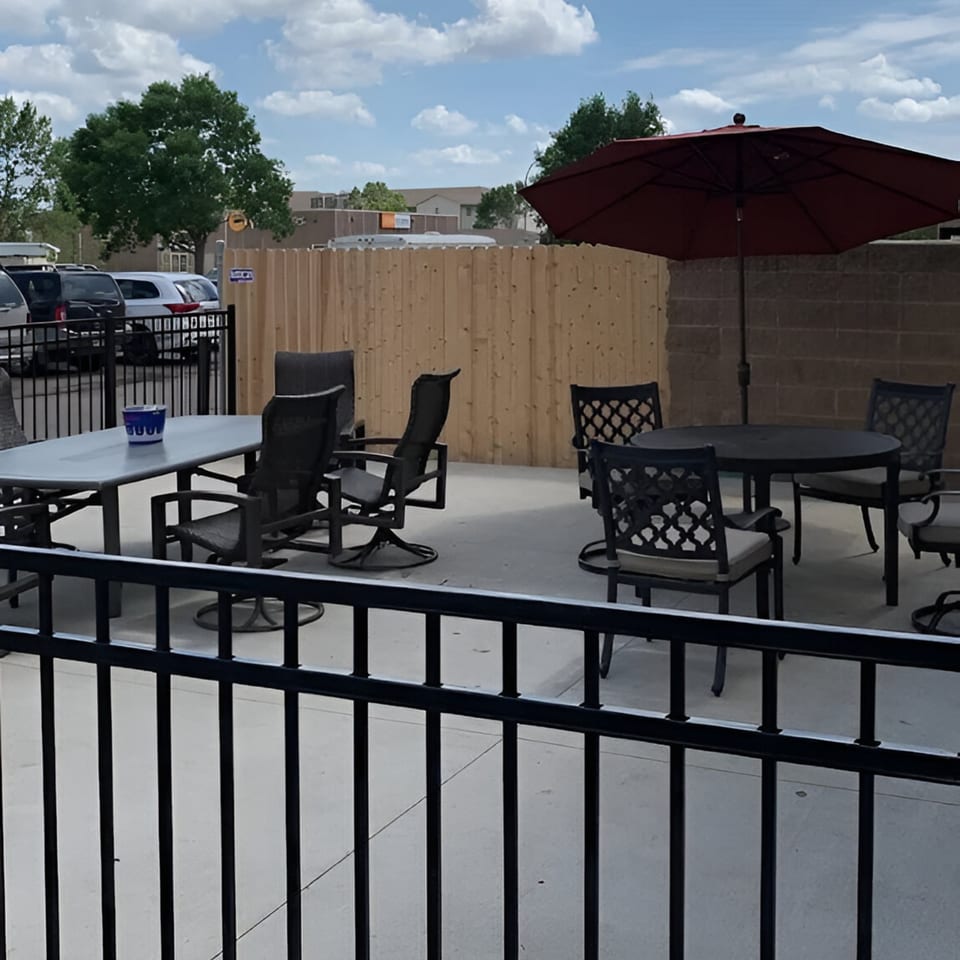 Outdoor patio at The Rush Bar & Grill with tables, chairs, and a large red umbrella.