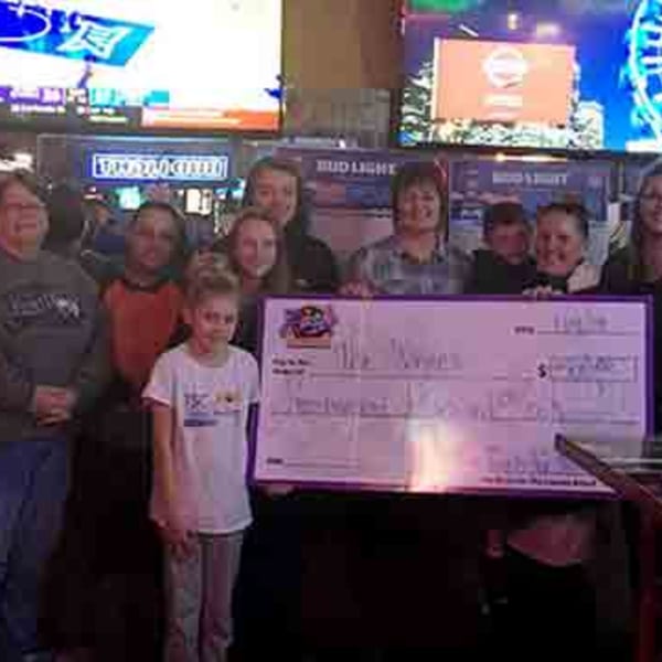 A group of people, including children, holding a large check at The Rush Bar & Grill.
