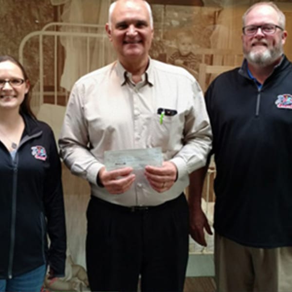 Three people, two men and one woman, smiling and holding a check from The Rush Bar & Grill.