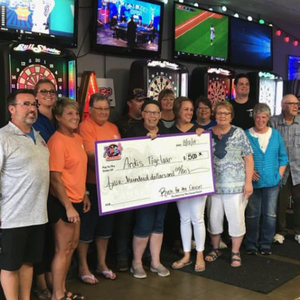 A group of people holding a large check for $500 at The Rush Bar & Grill.