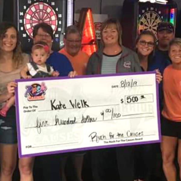 A group of people, including a baby, holding a large check for $500 from Rush for the Causes.