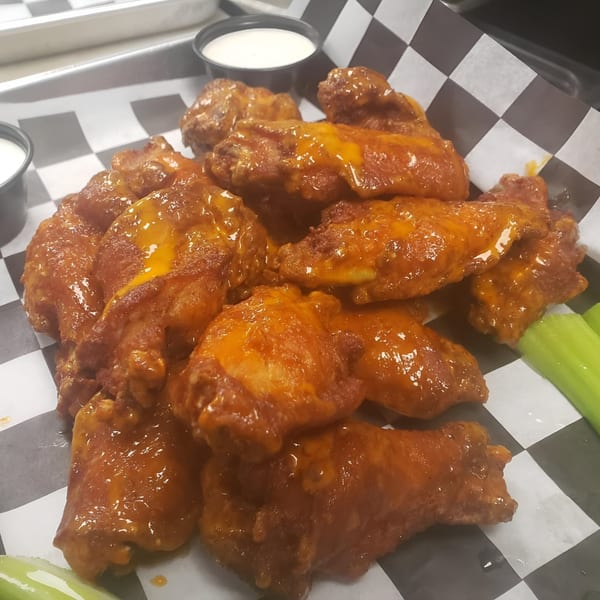 A platter of The Rush Bar & Grill's buffalo wings with celery sticks and dipping sauce.