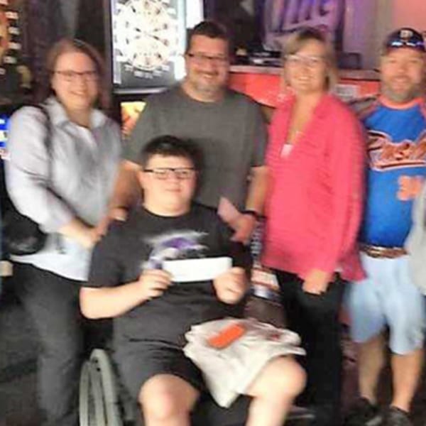 Five people, including a young man in a wheelchair, smiling together at The Rush Bar & Grill.
