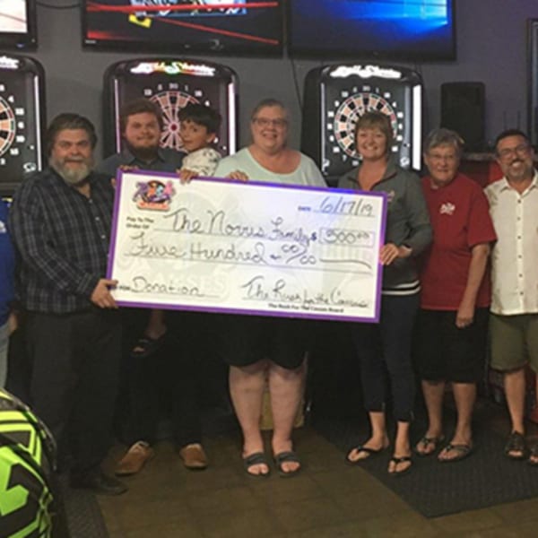 Seven people, including a child, hold a large check for $500 at The Rush Bar & Grill.