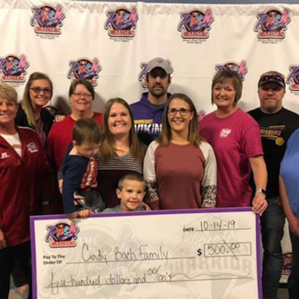 A group of adults and children from The Rush Bar & Grill holding a large check for $500.