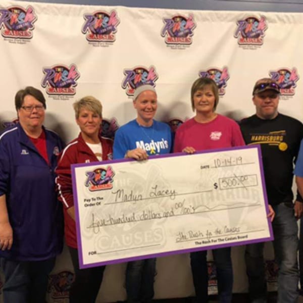 Five people from The Rush Bar & Grill present a large check for $500 to Madyn Lacey.