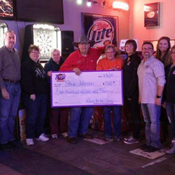 A group of people at The Rush Bar & Grill holding a large check for $1,500.