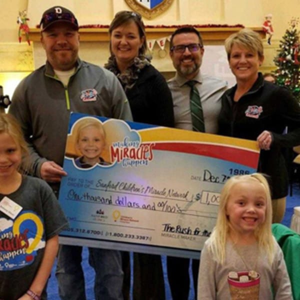 The Rush Bar & Grill staff presenting a $1,000 check to the Sanford Children's Miracle Network.
