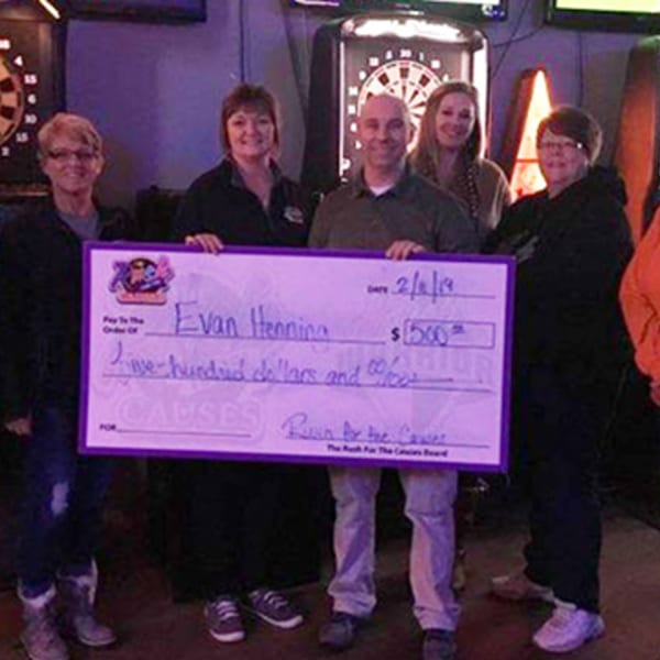 Five people from The Rush Bar & Grill holding a large check for "Rush for the Causes".
