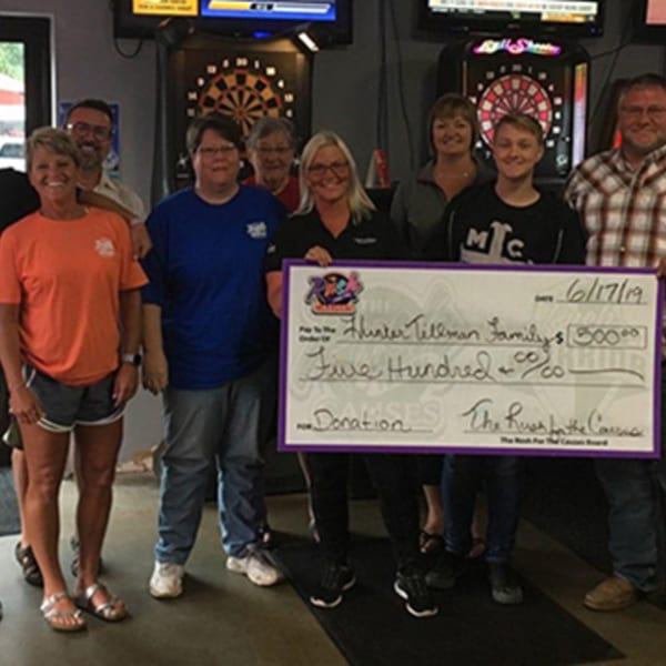 Group of people holding a large check for $500 donation to the Hunter Tillman Family at The Rush Bar & Grill.